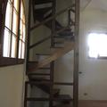 Scala in castagno a chiocciola su base quadrata con pertica centrale cosciali perimetrali e scalini a ventaglio con incasso sulla pertica su due piani