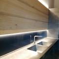 Rivestimento della parete della cucina con tavoloni di castagno verniciate effetto naturale con sagomature porta accessori e ganci