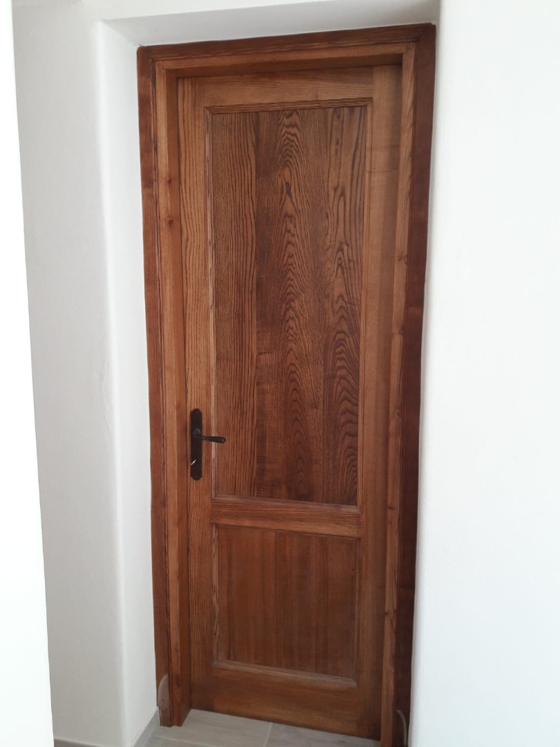 Porta interna in frassino a un anta con imbotte e listre a due formelle