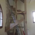 Scala in castagno a chiocciola su base quadrata con pertica centrale cosciali perimetrali e scalini a ventaglio con incasso sulla pertica su due piani