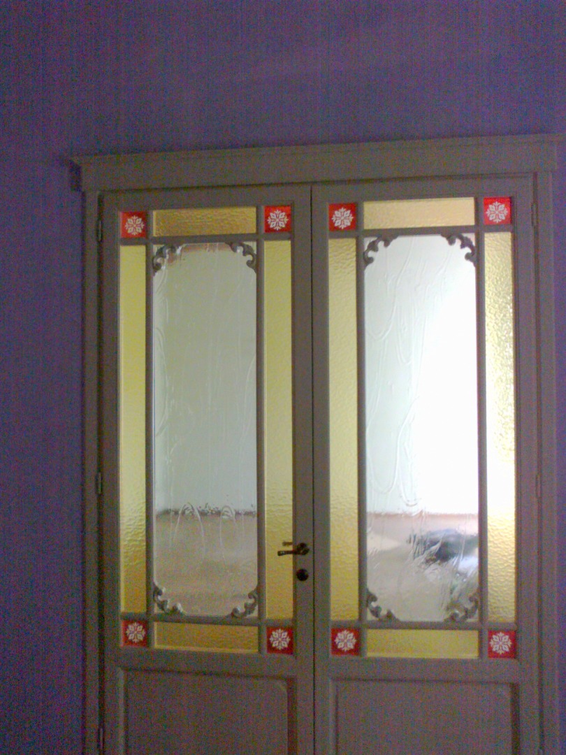 Porta a due ante all'inglese con formella bassa bacchette vetri colorati e fregi intagliati verniciata a smalto bianco