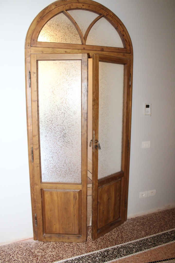 Restauro porta interna ad arco a due ante con rosta fissa decorata e formella bassa
